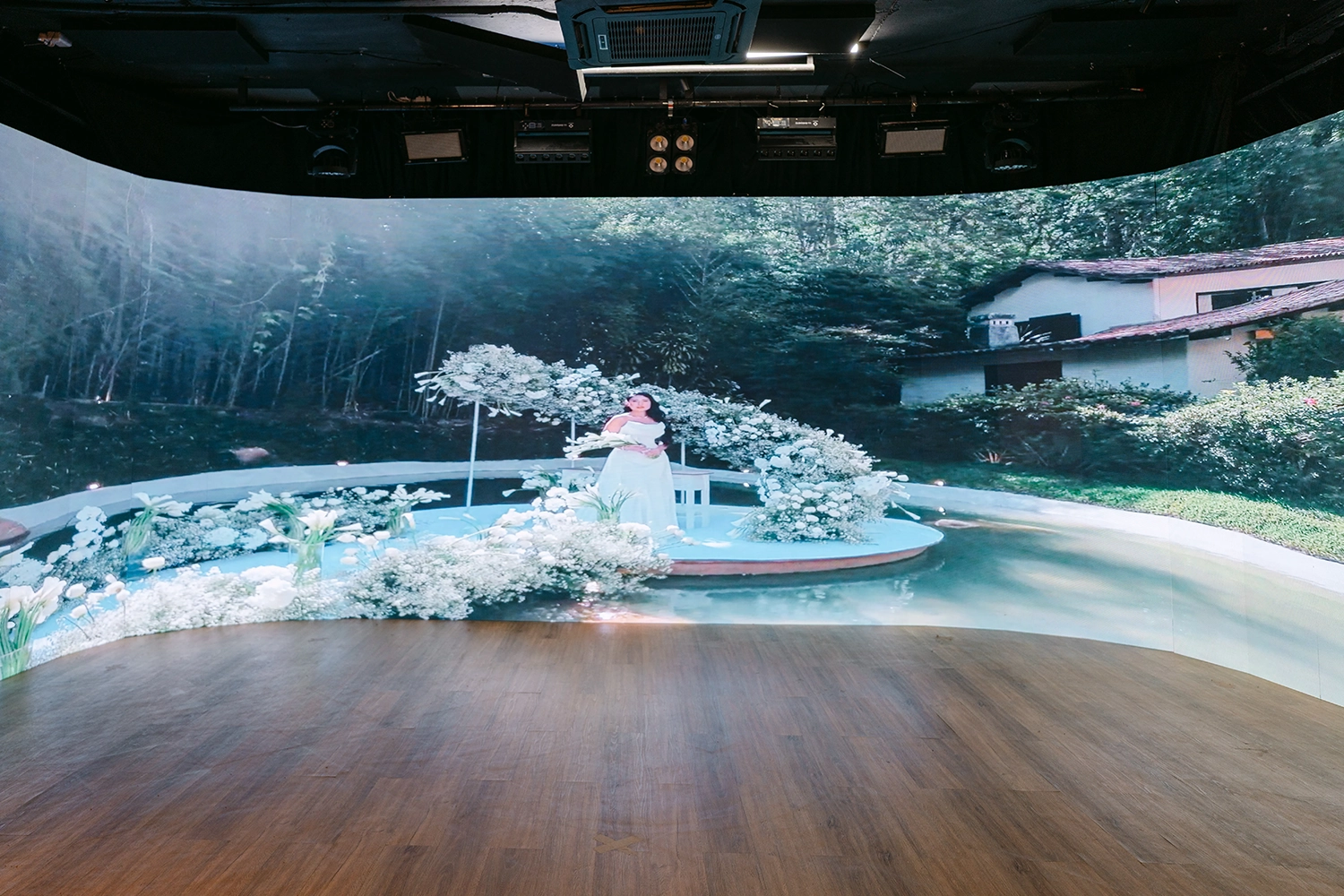 Painel de LED curvo exibindo um cenário de cerimônia com flores e jardim