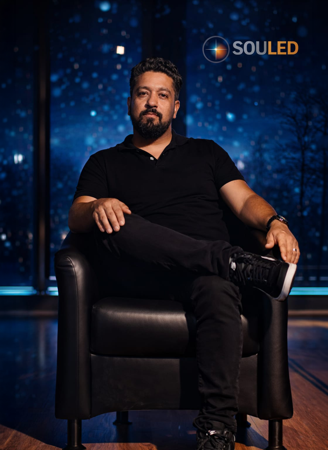 Elisio Neto sentado em uma poltrona diante de um fundo com a marca SouLed